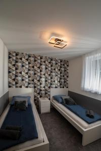 a bedroom with two beds and a wall with tiles at Melitta Vendégház in Magyarhertelend