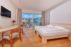 马尔切西内Eco Hotel Ariston的一间卧室，配有一张床、一张书桌和一扇窗户