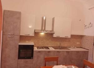 uma cozinha com armários brancos e um forno com placa de fogão em A' Ches du' Mestr 1 em Montalbano