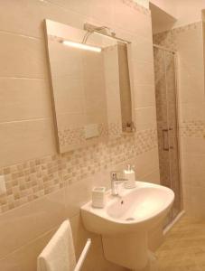 uma casa de banho com um lavatório e um chuveiro com um espelho. em A' Ches du' Mestr 1 em Montalbano