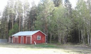 un fienile rosso con tetto blu di fronte a una foresta di Villa Polarktis a Överkalix