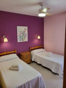 duas camas num quarto com paredes roxas em Casa Rural Reyes em Nuévalos