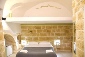 a bedroom with a bed in a stone wall at Minuetto 54 in Ostuni