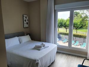 sypialnia z łóżkiem z ręcznikami i oknem w obiekcie Apartamentos Dunamar w mieście Noalla
