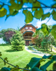 a large wooden house sitting on top of a lush green field at Villa Botanica in Mirkovec