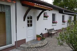 una casa blanca con una puerta y un banco en Bärenfalle, en Neuhardenberg