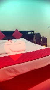 ein rotweißes Bett in einem Zimmer mit 2 Stühlen in der Unterkunft SRI VIGNESH RESIDENCY in Chennai
