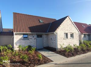 een wit bakstenen huis met een bruin dak bij Vakantiewoning Polderhuis 10, airco en verwarming in alle kamers, privé parkeerplaats en afgesloten tuin in Koksijde