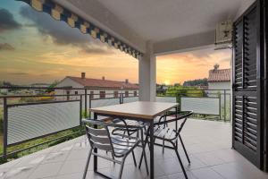 stół i krzesła na balkonie z widokiem na zachód słońca w obiekcie Apartment in Porec/Istrien 10190 w Poreču