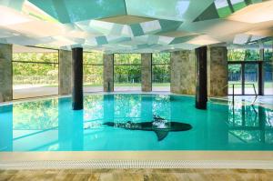 duży basen z błękitną wodą w budynku w obiekcie Apartament z aneksem kuchennym i basenem 426 Diune Hotel Resort w Kołobrzegu