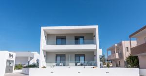 a white apartment building with a blue sky in the background at NM Apartments in Mastichari