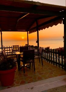 um pátio com uma mesa e cadeiras e o oceano em Riviera Hotel em Poros