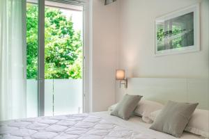 a white bedroom with a bed and a window at Hotel Centrale in Lignano Sabbiadoro