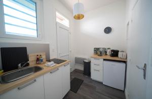 eine Küche mit weißen Schränken und einer Spüle und einem Fenster in der Unterkunft AppartUnique - Chez Layette in Vichy + 2 Fotos