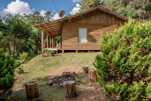 a small wooden cabin in a field with trees at Sítio flor da montanha in São Bento do Sapucaí