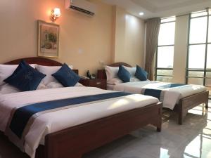1 dormitorio con 2 camas y almohadas azules y blancas en A1 Hotel, en Phnom Penh