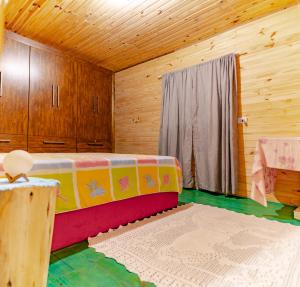 a room with a bed in a wooden cabin at Sítio flor da montanha in São Bento do Sapucaí