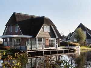 una casa en un muelle sobre el agua en Beautiful, thatched villa with a sauna at the Tjeukemeer, en Delfstrahuizen