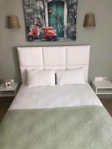 a bedroom with a white bed with a scooter on the wall at THE GEORGE APARTMENTS in Nea Kalikratia