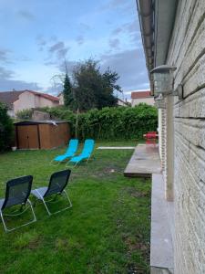 dos sillas azules sentadas en el césped en un patio en Villa Tenjin chambre 16 en Bondy