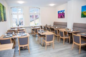 un comedor con mesas, sillas y ventanas en Hotel Fulda en Hannoversch Münden