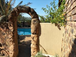 a stone archway next to a wall with a swimming pool at Botties Shemah in Pretoria