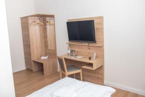 Zimmer mit einem Schreibtisch, einem TV und einem Bett in der Unterkunft Hotel Fulda in Hannoversch Münden