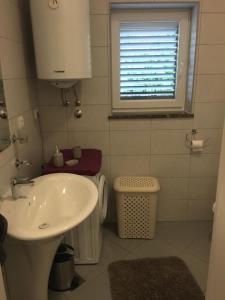 La salle de bains est pourvue d'un lavabo, de toilettes et d'une fenêtre. dans l'établissement Nikka Apartments, à Malinska