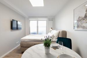 a white room with a bed and a table and chairs at Apartment Gartenblick - 1 Zi, Küche, Duschbad, Terrasse sowie Gartenmitbenutzung in Bayreuth