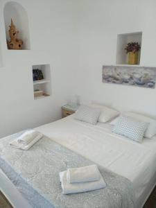 a white bed with two towels on top of it at Melissou place in Apollonia