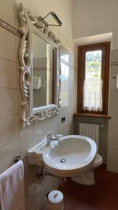Baño blanco con lavabo y espejo en Podere Montese Country House, en San Gimignano