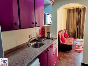 a kitchen with purple cabinets and a sink at Chalets in Porto Matrouh Families Only in Marsa Matruh
