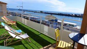 a balcony with chairs and a table and a boat at Mon P'tit Hôtel in Le Grau-dʼAgde
