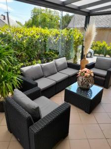 a patio with wicker chairs and a couch and a table at MELÁNIA in Vonyarcvashegy