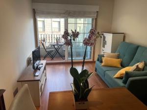 Una sala de estar con un sofá azul y una mesa. en Soños Sanxenxo, en Sanxenxo 2 fotos más