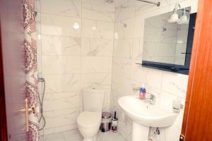 a white bathroom with a toilet and a sink at Cico Hostel &private room in Gjirokastër