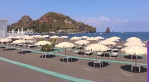 a bunch of umbrellas on a beach with the ocean at Les Sables Noirs & Spa Multiproprietà in Vulcano