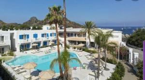 a resort with a swimming pool and palm trees at Les Sables Noirs & Spa Multiproprietà in Vulcano