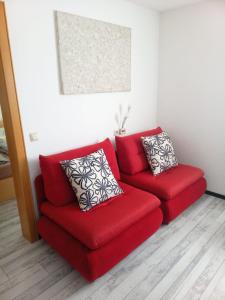 a red couch with two pillows in a living room at Dimai House No 17 Dornbirn Zentrum in Dornbirn