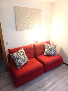 um sofá vermelho com duas almofadas num quarto em Dimai House No 17 Dornbirn Zentrum em Dornbirn