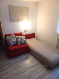 een slaapkamer met een bed en een rode bank bij Dimai House No 17 Dornbirn Zentrum in Dornbirn