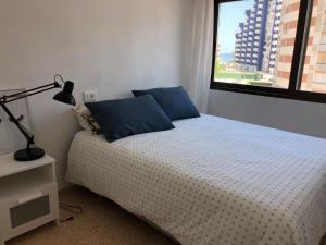 sypialnia z łóżkiem z niebieskimi poduszkami i oknem w obiekcie Apartamento Ca Batallera Playa Gandia w mieście Playa de Gandia