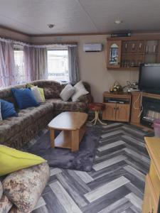 een woonkamer met een bank en een tafel bij Lochlands caravan park X(6) in Forfar