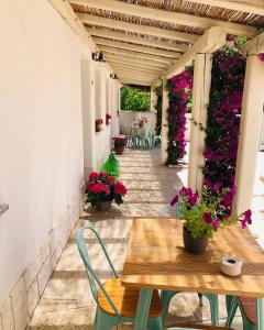 a patio with a table and chairs and flowers at Domus Deiana Case Vacanza in San Giovanni Suèrgiu