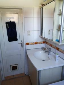 ein Badezimmer mit einem Waschbecken, einem Spiegel und einer Tür in der Unterkunft Doppelhaushälfte mit Garten in Linz