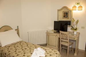 1 dormitorio con 1 cama y escritorio con TV en Toscana Wellness Resort, en Arcidosso