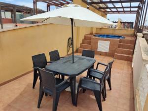 a table and chairs with an umbrella on a balcony at ATICO LAGUNA BEACH con JACUZZY PRIVADO in Vera