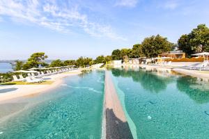 a pool with blue water next to a beach at Rosmarin&Olive Premium Mobile Homes in Selce