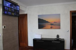 a bathroom with a tv on the wall and a sink at Apartamentos Zarautz Playa, con piscina y garaje in Zarautz