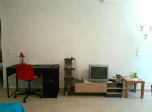 Zimmer mit einem Schreibtisch, einem TV und einem Stuhl in der Unterkunft Quiet, colourful home in Cyclades in Konizopí
